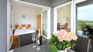 A room with a bed, a table with a bottle and glasses, and a potted plant.