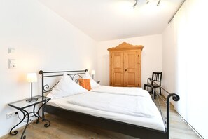 A bedroom with a bed, bedside tables, a wooden wardrobe, and a chair.