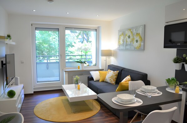 A modern living room with a sofa, coffee table, and dining table.
