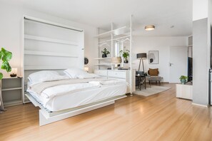 A modern bedroom with a bed, built-in shelving, a desk, and a chair.