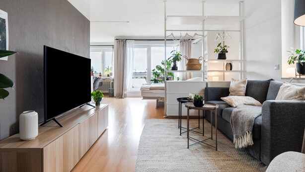 A modern living room with a flat-screen TV, a sofa, a coffee table, and a TV stand.