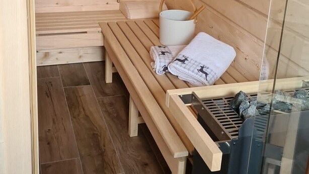 Ein Holzsaunaraum mit Bänken, einem Eimer und einer Saunaheizung.