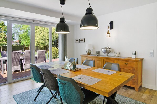 Un espace repas comprenant une table en bois, des chaises et des luminaires suspendus.