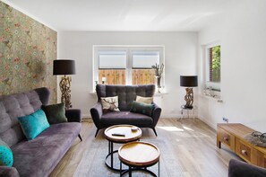 Un salon comprenant un canapé, deux fauteuils, une table basse et une table d’appoint avec une lampe.