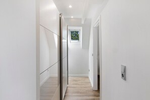 Un pasillo estrecho con tragaluz, una puerta y un interruptor de luz.
