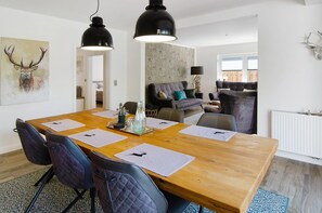 Un coin repas avec une table en bois, des chaises noires et un lustre.