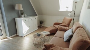 A modern living room with a brown sofa, a white cabinet, and a round coffee table.