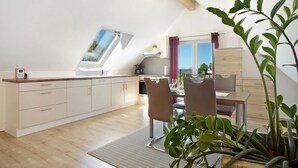 Eine moderne Küche mit Oberlicht, Holzbalkendecke, einem Essbereich mit Stühlen und einer großen Pflanze.