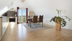 Eine moderne Küche mit Essbereich, einem Balkon und einer großen Küstertopf-Pflanze.