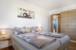 Ein Schlafzimmer mit zwei Betten, einem Holzschrank und einem Wandbild.