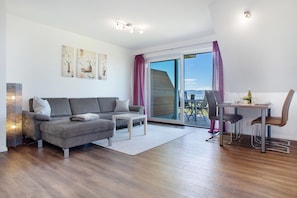 Een moderne woonkamer met een bank, een eettafel met stoelen, een grote schuifpui en kunst aan de muur.