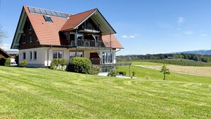 A two-story house with a sloped roof, a balcony, and solar panels. - Apartment '2' with Lake View, Shared Garden and Wi-Fi (Kressbronn am Bodensee)