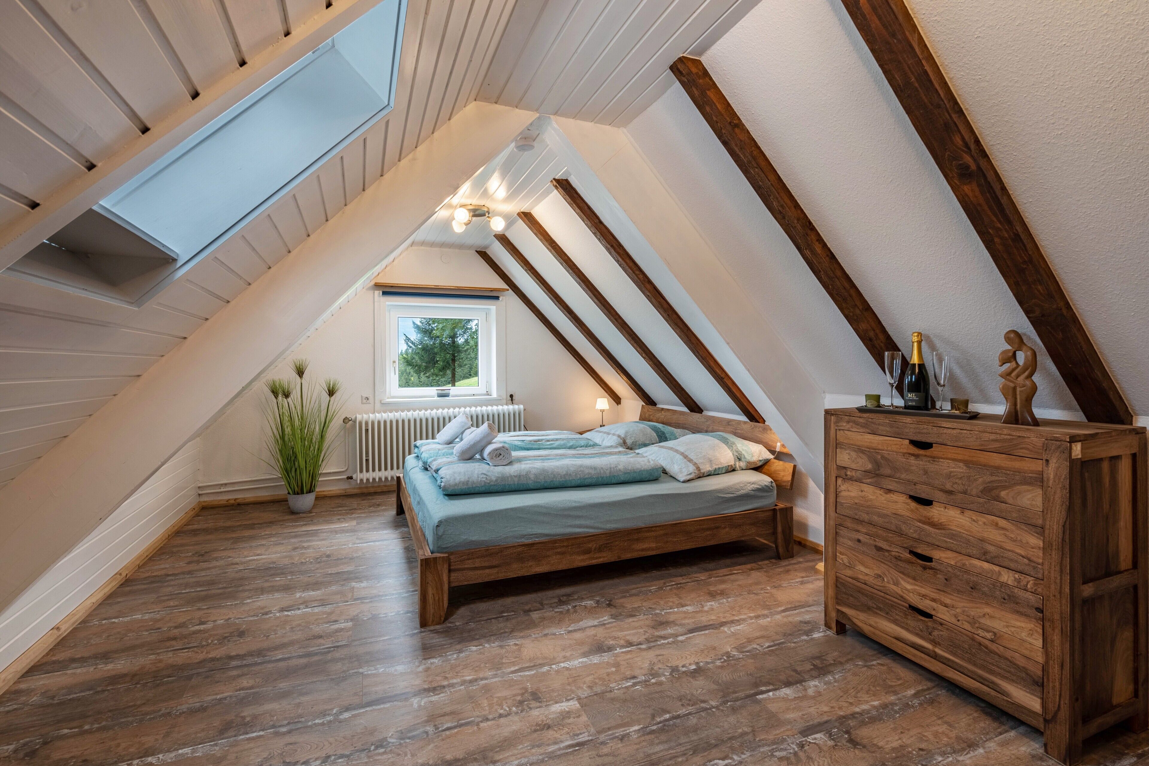 A sloped ceiling room with a bed, wooden dresser, and a radiator.