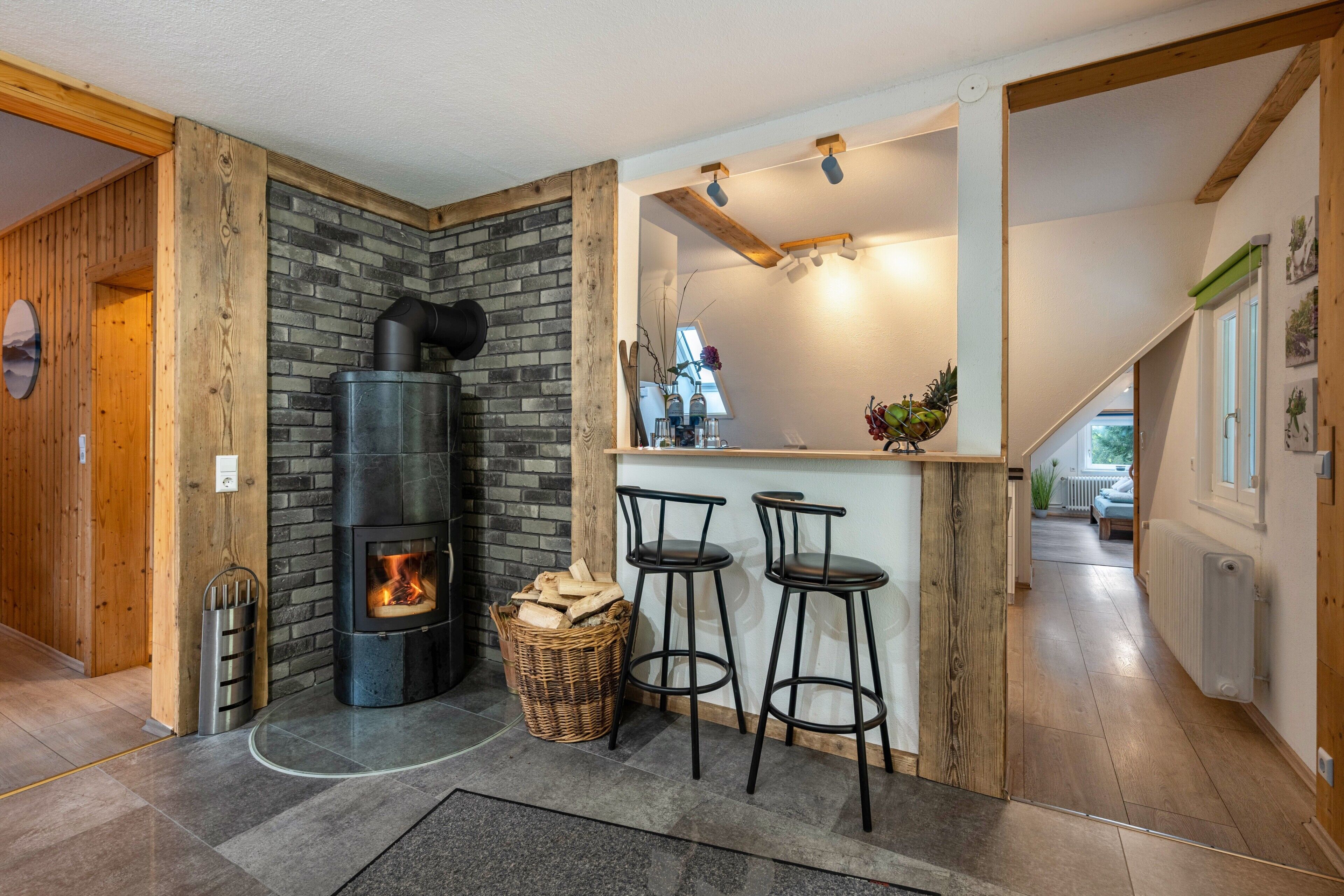 A modern kitchen with a built-in wood stove, a bar area with stools, and a stone wall.