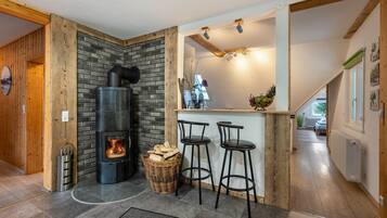 A modern kitchen with a built-in wood stove, a bar area with stools, and a stone wall.