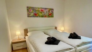 A double bed with white linens, two bedside lamps, and a painting above the bed. - Apartment "Am Berg" with Panoramic Views, Terrace, Grill, Parking (Müllheim im Markgräflerland)