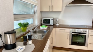 A modern kitchen with a stainless steel range, microwave, and coffee maker. - Apartment "Am Berg" with Panoramic Views, Terrace, Grill, Parking (Müllheim im Markgräflerland)