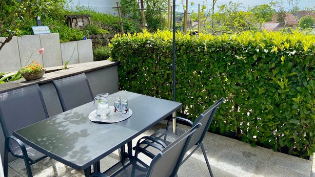 An outdoor patio with a table, chairs, and an umbrella. - Apartment "Am Berg" with Panoramic Views, Terrace, Grill, Parking (Müllheim im Markgräflerland)