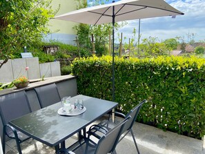 Une terrasse extérieure avec une table, des chaises et un parasol.