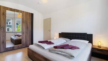 Ein modernes Schlafzimmer mit einem großen Bett, einem Holzschrank und einem Spiegel.
