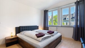 Une chambre à coucher avec un lit, une table de chevet et une fenêtre avec des rideaux.