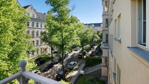 Une rue résidentielle bordée de voitures garées, d’arbres et d’immeubles à plusieurs étages.