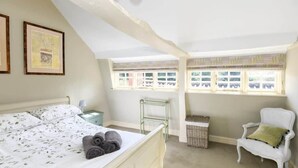 A bedroom with a bed, a chair, a window, and a small table. - Beautiful Georgian Cottage near Frome (Beckington)