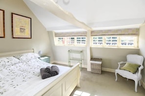 A bedroom with a bed, a chair, a window, and a small table. - Beautiful Georgian Cottage near Frome (Beckington)