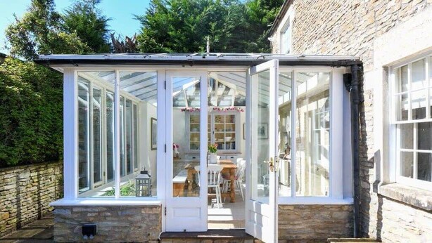 A conservatory with glass doors, a stone wall, and a stone floor. - Beautiful Georgian Cottage near Frome (Beckington)