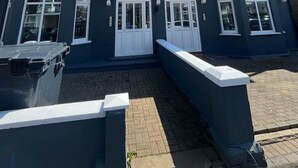 Un bâtiment à deux étages doté d’un balcon, de grandes fenêtres et d’un chemin en briques menant à l’entrée.