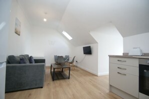 A modern apartment with a living room, dining area, kitchen, and a TV mounted on the wall. - Snug Margate Apartment (Margate)