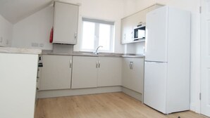 A modern kitchen with white cabinets, a built-in oven, and a refrigerator. - Snug Margate Apartment (Margate)