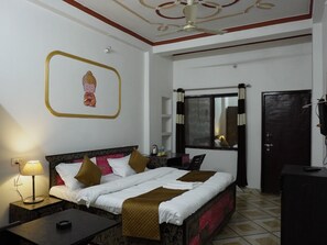 A hotel room with a bed, bedside table, lamp, and a ceiling fan.