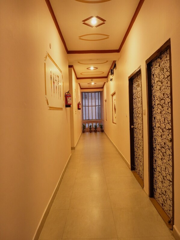 A hallway with a tiled floor, a ceiling with recessed lighting, and a door with a floral pattern.