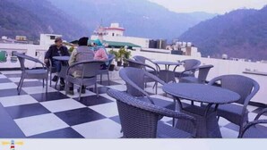 Habitación con tetera decorativa amarilla, suelo a cuadros, muebles de mimbre y vistas a montañas.