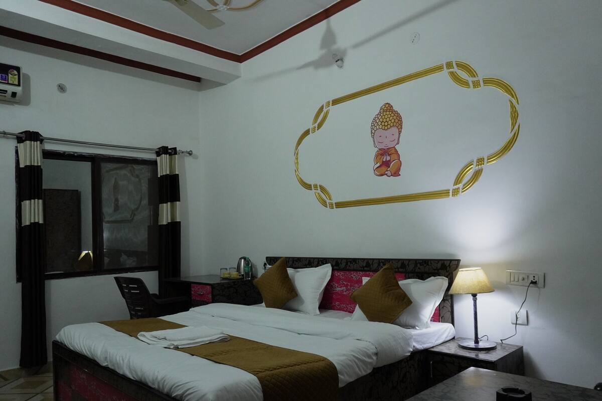 Ein Hotelzimmer mit Bett, Nachttisch mit Lampe, Wanddekoration und einem Fenster mit Vorhängen.
