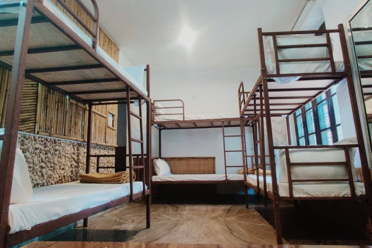 Ein Schlafsaalzimmer mit Etagenbetten, einer Steinwand und einem Holzboden.