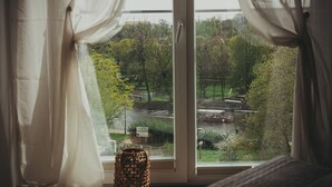 Une pièce dotée d’une grande fenêtre, de rideaux légers et d’un vase décoratif posé sur le rebord de la fenêtre.