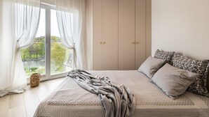 Une chambre avec un grand lit, une armoire et une vue sur la verdure.
