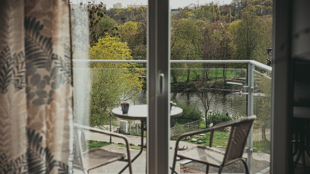 Un balcon donnant sur un lac, entouré d’arbres et muni d’une balustrade.