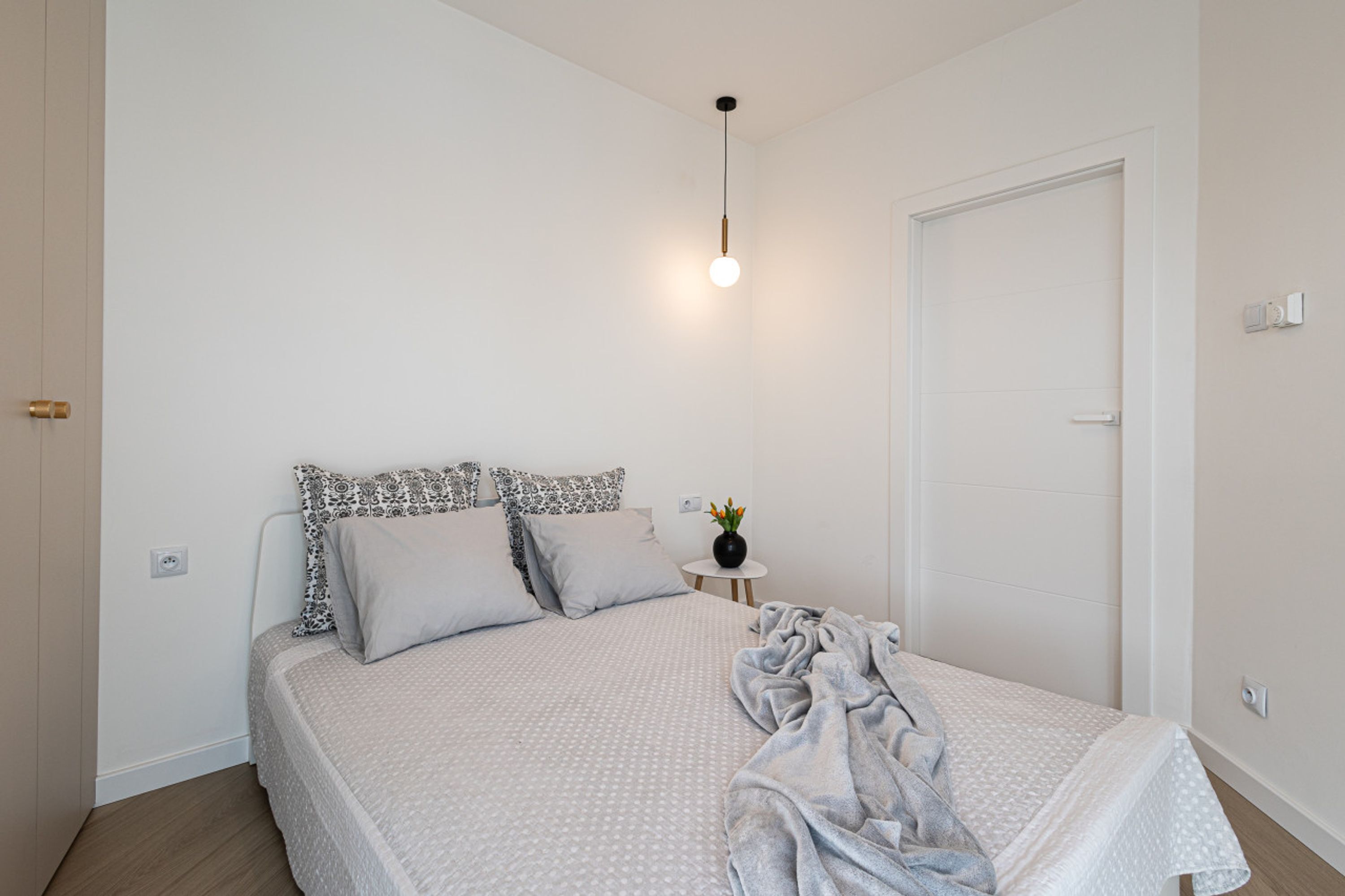 Une chambre à coucher avec un lit, une table de chevet et un luminaire suspendu.