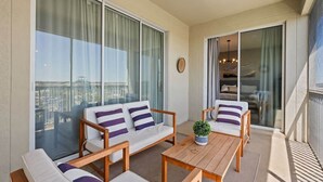 Un balcon avec un ensemble de meubles de salon, une table et une plante en pot.