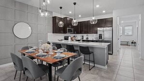 Une cuisine moderne avec des meubles de couleur sombre, un îlot central et des luminaires suspendus.