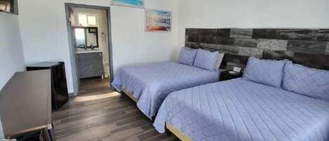 Un dormitorio con cama, ventilador de techo y piso de madera.
