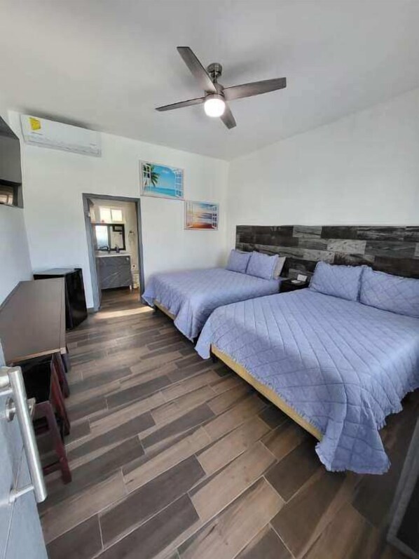 Une chambre à coucher avec un lit, un ventilateur de plafond et un plancher en bois.