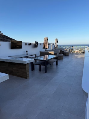 A rooftop terrace with a glass table, wicker chairs, and a white railing overlooking the sea. - CUATRO PALMAS HOTEL  (Puerto Peñasco)