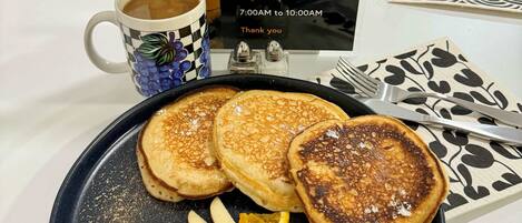 Un menu de petit-déjeuner proposé dans un hôtel, comprenant des crêpes, des fruits et du café.