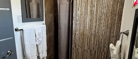 Un baño moderno con una bañera grande, una ducha con cortina, un inodoro y un perchero para toallas.