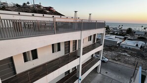 Un immeuble à plusieurs étages, doté d’une architecture moderne, avec des balcons et un espace de stationnement.