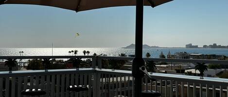 A balcony with a view of the sea and a distant mountain.